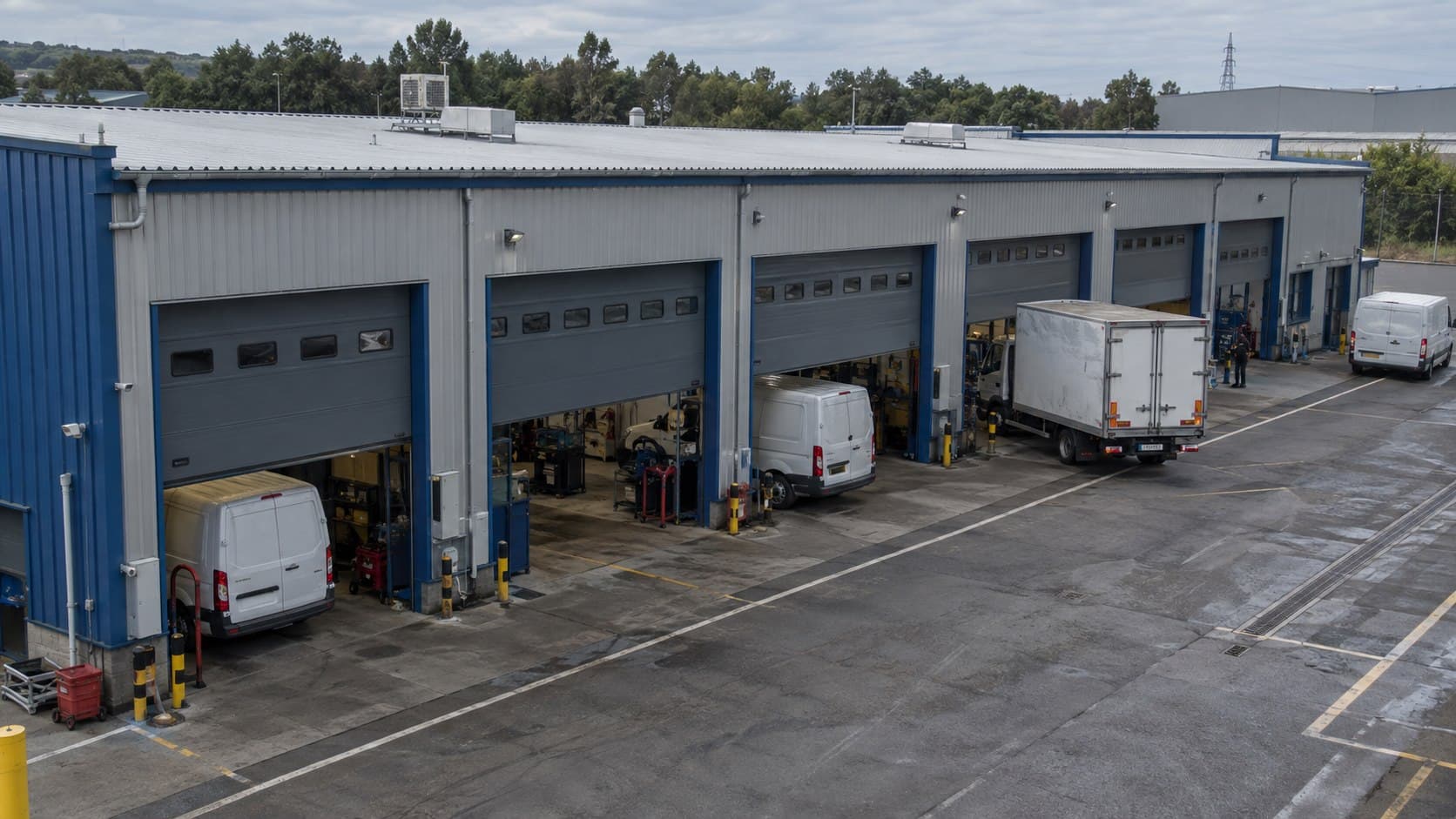 Multi-bay fleet garage with service vans parked outside