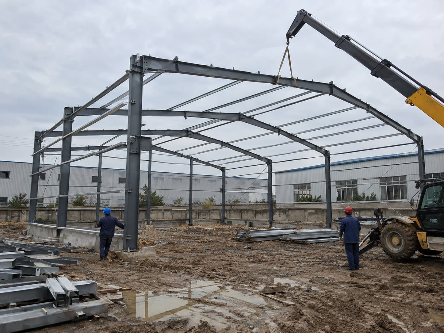 Steel portal frame for a metal garage being erected by crane